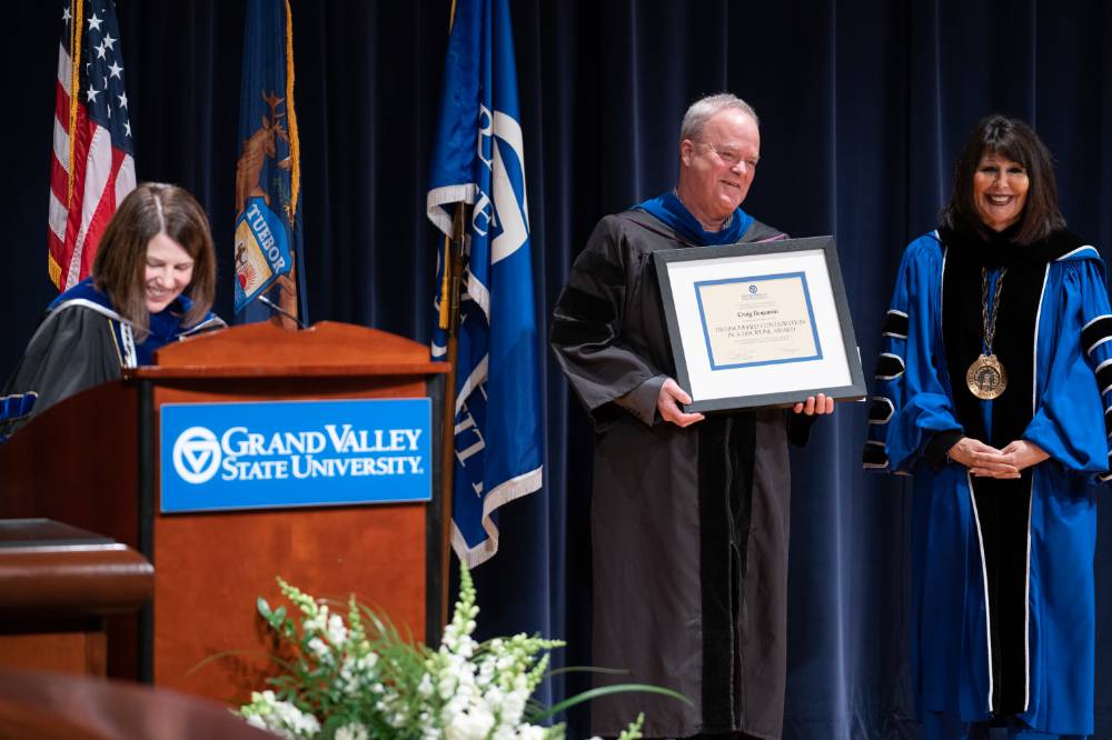 Provost and President smile as Craig Benjamin holds his award